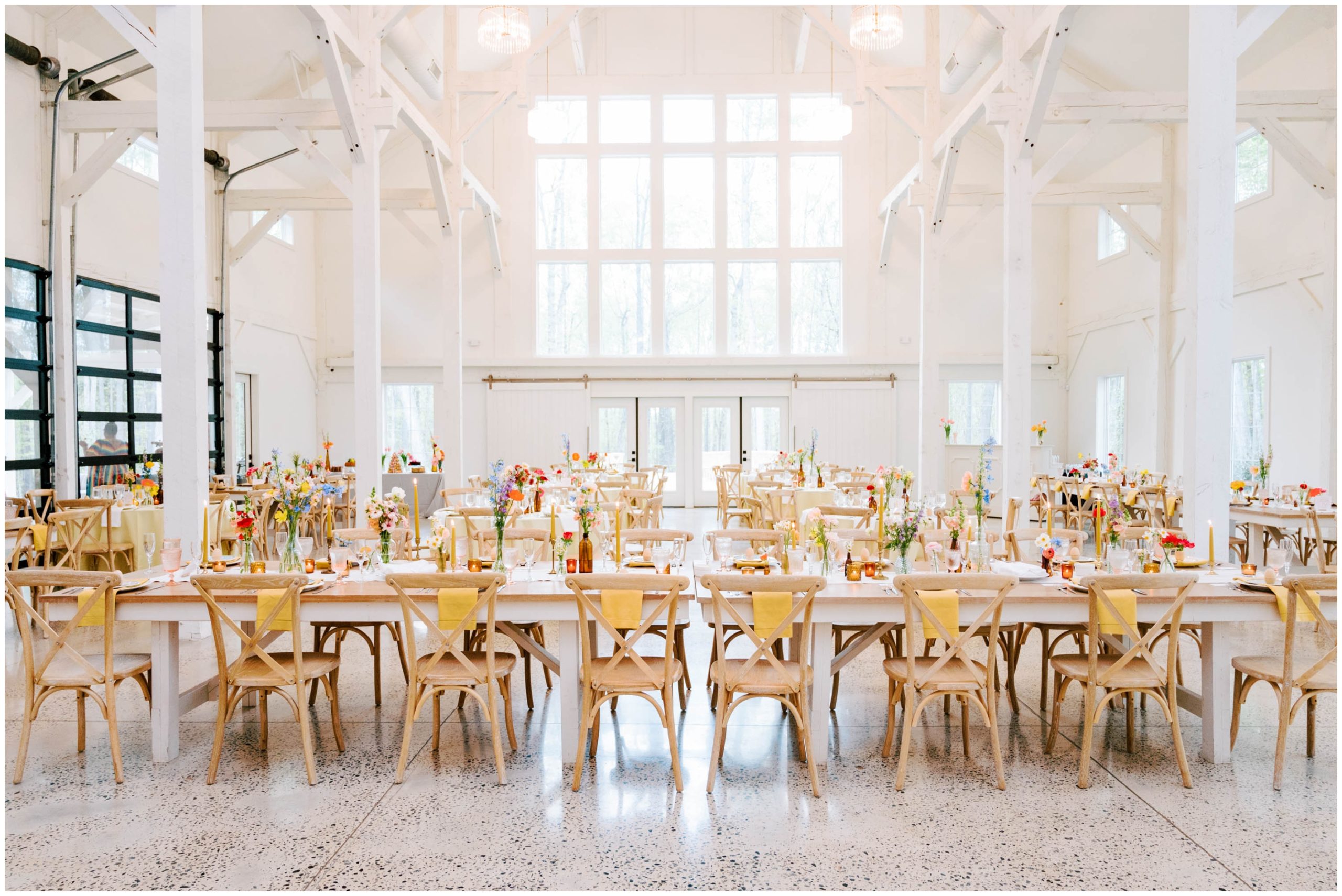 White and yellow table linens, amber votives, and colorful florals for a spring wedding reception