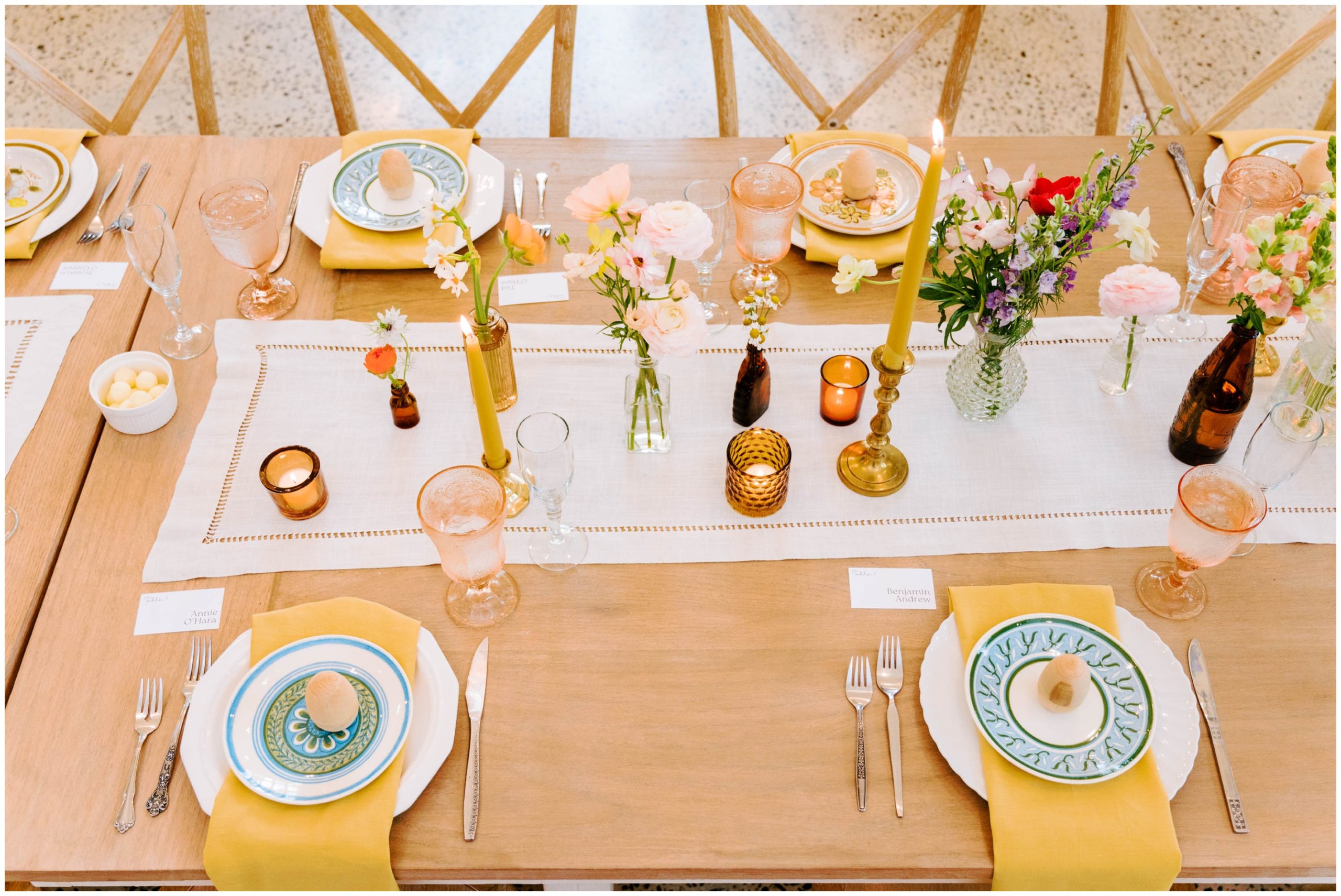 White and yellow table linens, amber votives, and colorful florals for a spring wedding reception