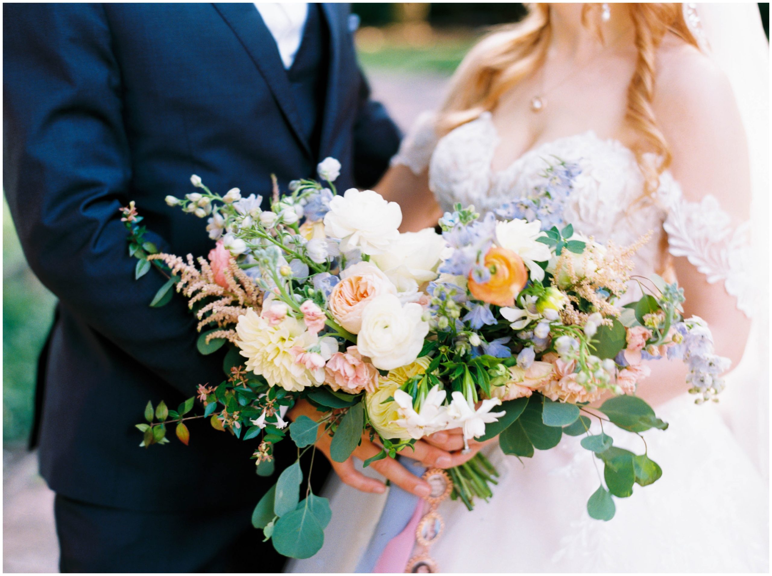 Bridal bouquet filled with white and peach roses, white dahlia, and blue delphinium by Once Gathered